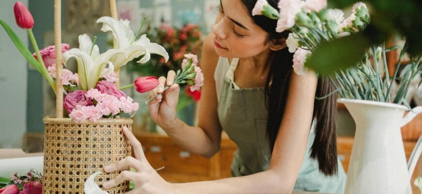A woman arranges flowers in a basket